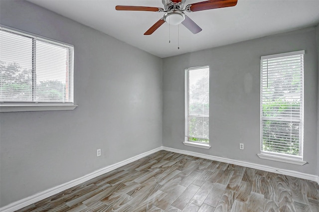 empty room featuring baseboards, wood finished floors, plenty of natural light, and a ceiling fan