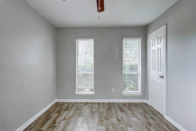 spare room featuring wood finished floors, ceiling fan, and baseboards