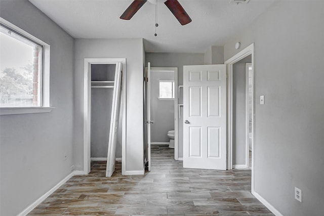 unfurnished bedroom with wood finished floors, a closet, baseboards, and ceiling fan