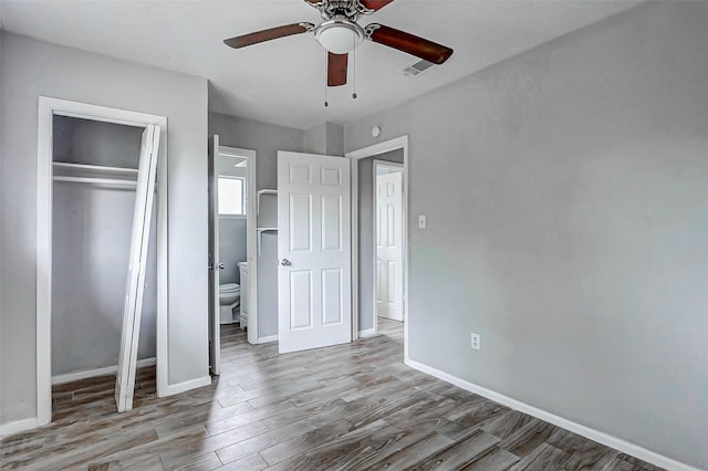unfurnished bedroom featuring wood finished floors, a closet, baseboards, and ceiling fan