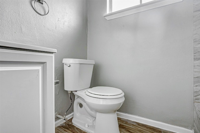 bathroom with toilet, baseboards, and wood finished floors