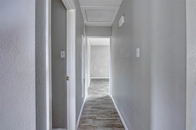 corridor with baseboards and wood finished floors