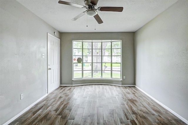 unfurnished room featuring wood finished floors, ceiling fan, and baseboards