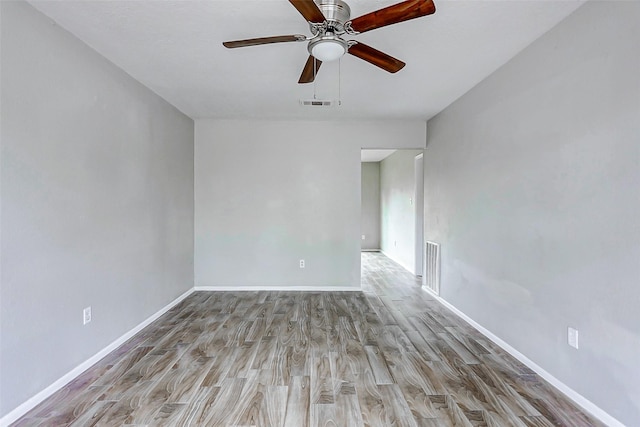 unfurnished room with ceiling fan, wood finished floors, and baseboards