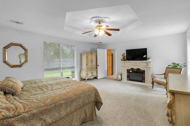 24930 Plantation Estates Ave, Porter, TX 77365 - bedroom featuring carpet flooring, a glass covered fireplace, a tray ceiling, and a ceiling fan
