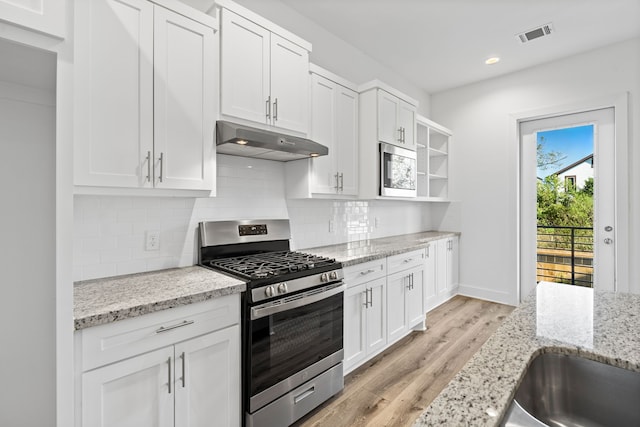 5615 Savyon Dr, Houston, TX 77091 - kitchen featuring appliances with stainless steel finishes, under cabinet range hood, light wood finished floors, white cabinetry, and open shelves