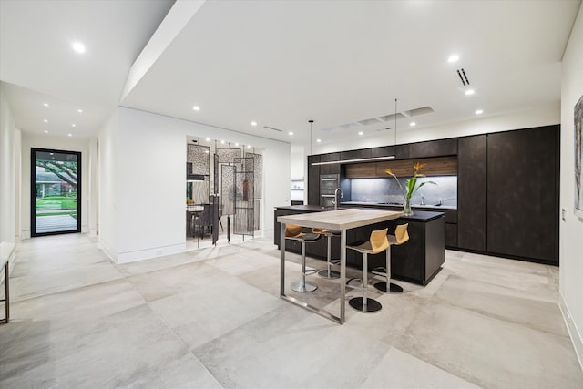 5686 Bayou Glen Rd, Houston, TX 77056 - kitchen with modern cabinets, a center island with sink, recessed lighting, a breakfast bar, and dark brown cabinets