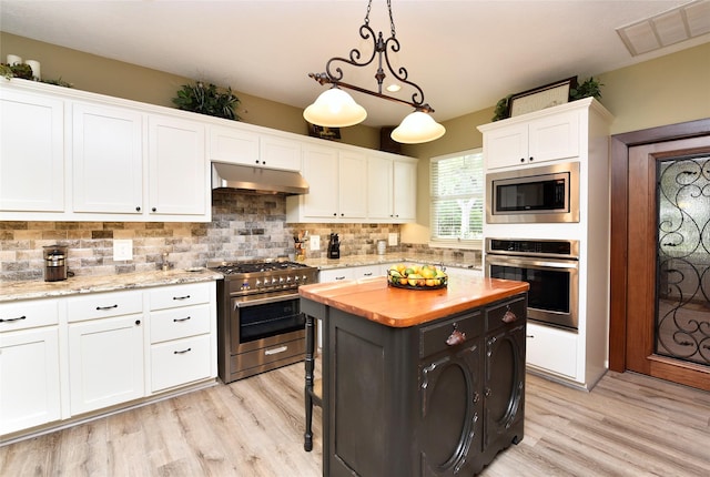 kitchen featuring stainless steel appliances, wood counters, white cabinets, and light wood-type flooring
