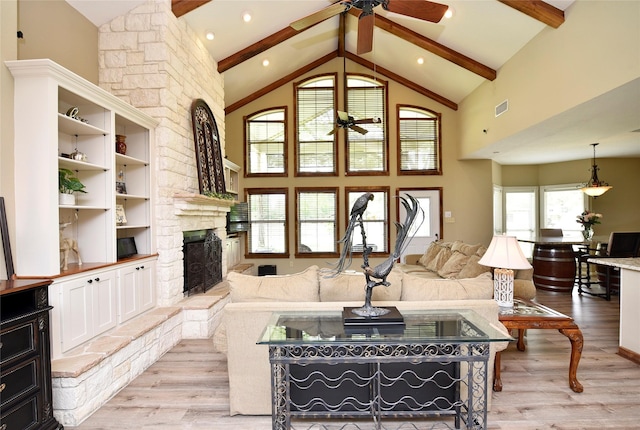 living room featuring ceiling fan, beam ceiling, light wood finished floors, high vaulted ceiling, and a fireplace