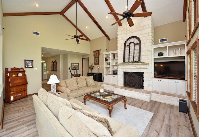 living area with a ceiling fan, high vaulted ceiling, a stone fireplace, wood finished floors, and beam ceiling