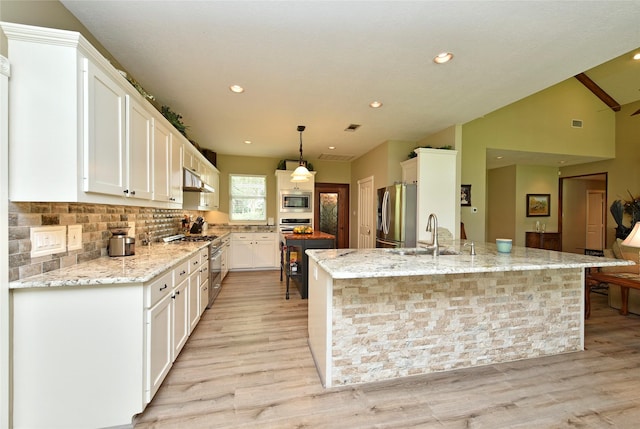 kitchen with appliances with stainless steel finishes, a sink, white cabinetry, light wood-style flooring, and a center island