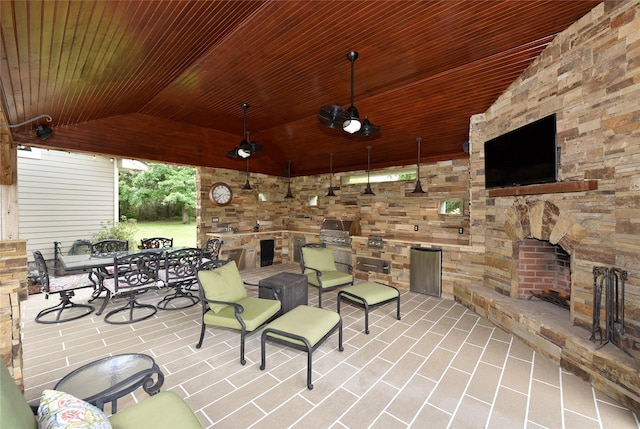view of patio / terrace featuring an outdoor stone fireplace, an outdoor kitchen, outdoor dining space, and ceiling fan