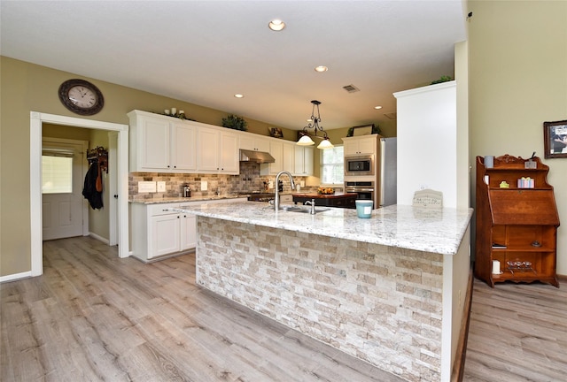 kitchen featuring stainless steel appliances, under cabinet range hood, light wood-type flooring, white cabinetry, and recessed lighting