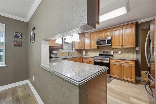 985 Sunnyside Dr, Bridge City, TX 77611 - kitchen featuring stainless steel appliances, a textured wall, a sink, light wood finished floors, and ornamental molding