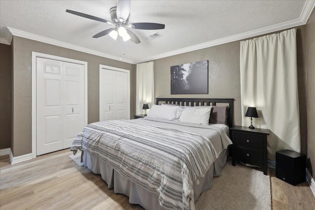 985 Sunnyside Dr, Bridge City, TX 77611 - bedroom with light wood-type flooring, multiple closets, ornamental molding, a textured wall, and a textured ceiling