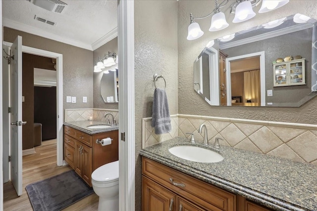 985 Sunnyside Dr, Bridge City, TX 77611 - bathroom with crown molding, a textured wall, wood finished floors, two vanities, and tasteful backsplash