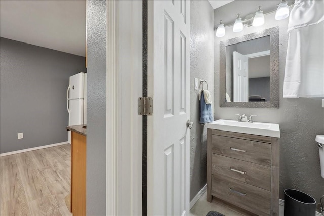 985 Sunnyside Dr, Bridge City, TX 77611 - half bath featuring vanity, wood finished floors, baseboards, and a textured wall