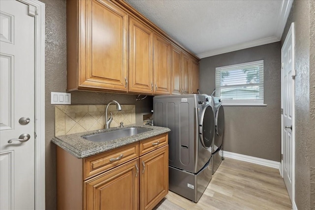 985 Sunnyside Dr, Bridge City, TX 77611 - laundry area featuring washer and clothes dryer, cabinet space, crown molding, baseboards, and light wood finished floors