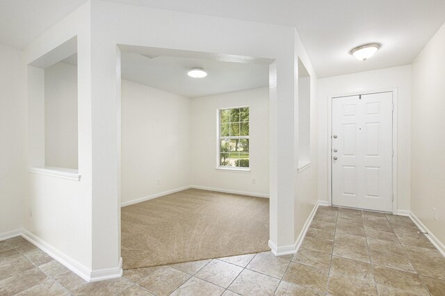 entryway with light colored carpet, baseboards, and light tile patterned flooring