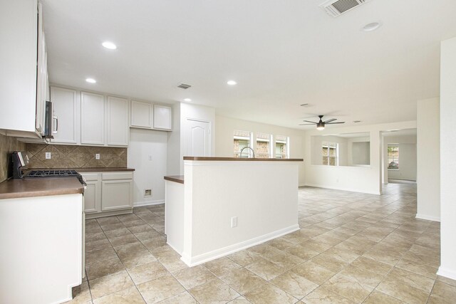 kitchen with a ceiling fan, range with gas stovetop, decorative backsplash, recessed lighting, and white cabinets