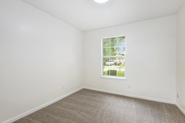 unfurnished room with carpet and baseboards