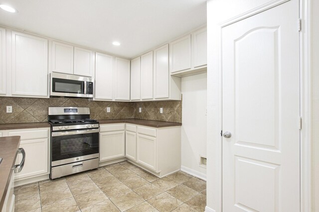 kitchen with stainless steel appliances, dark countertops, recessed lighting, tasteful backsplash, and white cabinets