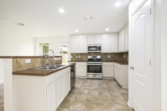 kitchen featuring stainless steel appliances, a sink, decorative backsplash, dark countertops, and recessed lighting