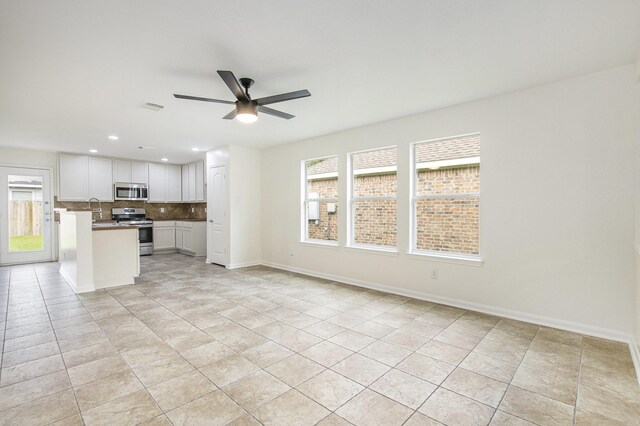 unfurnished living room with a sink, light tile patterned floors, a ceiling fan, recessed lighting, and baseboards