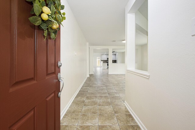 foyer entrance featuring baseboards and light stone finish floors