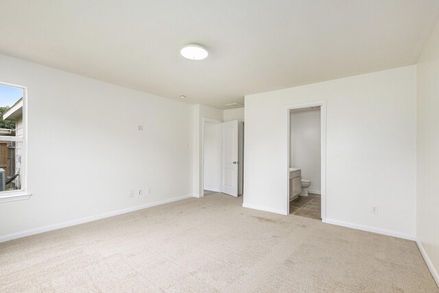 unfurnished bedroom featuring carpet flooring, baseboards, and ensuite bath