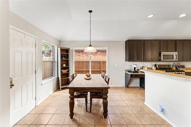 kitchen with appliances with stainless steel finishes, hanging light fixtures, dark brown cabinets, light countertops, and light tile patterned floors