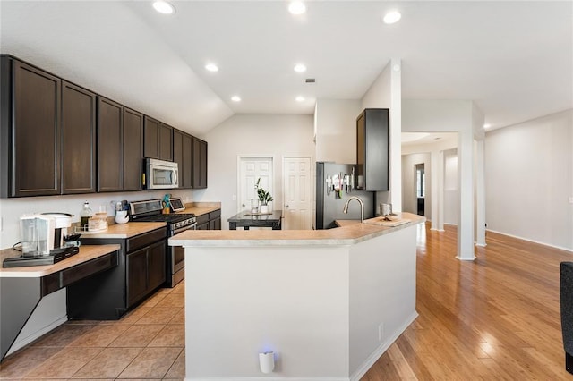 kitchen with stainless steel appliances, light countertops, dark brown cabinets, recessed lighting, and a peninsula