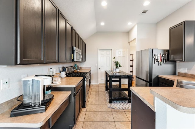 kitchen featuring stainless steel appliances, light countertops, light tile patterned floors, lofted ceiling, and recessed lighting