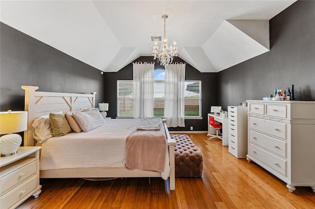 bedroom with a chandelier, light wood-style flooring, and vaulted ceiling