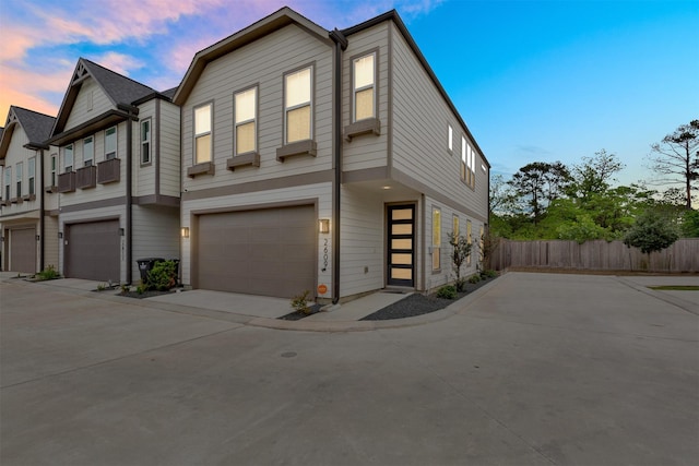 view of front of home with a garage, concrete driveway, and fence
