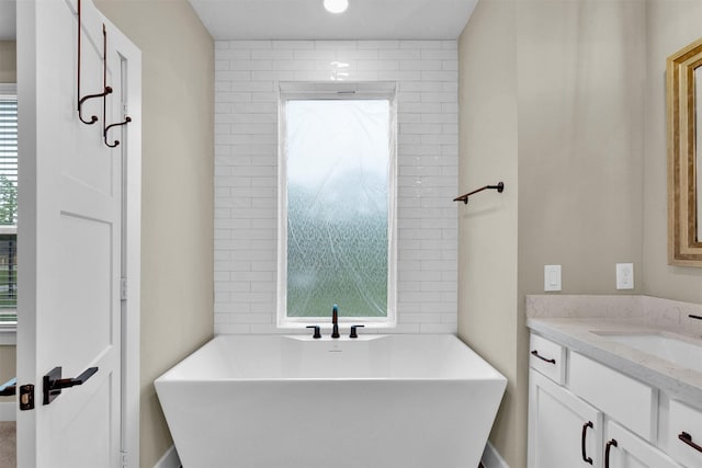 bathroom with vanity, a freestanding tub, and recessed lighting