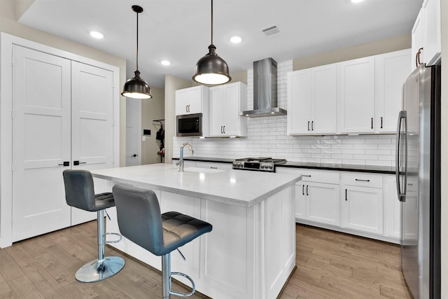 2609 Paul Quinn St, Houston, TX 77091 - kitchen with appliances with stainless steel finishes, wall chimney range hood, light wood-style flooring, white cabinets, and recessed lighting