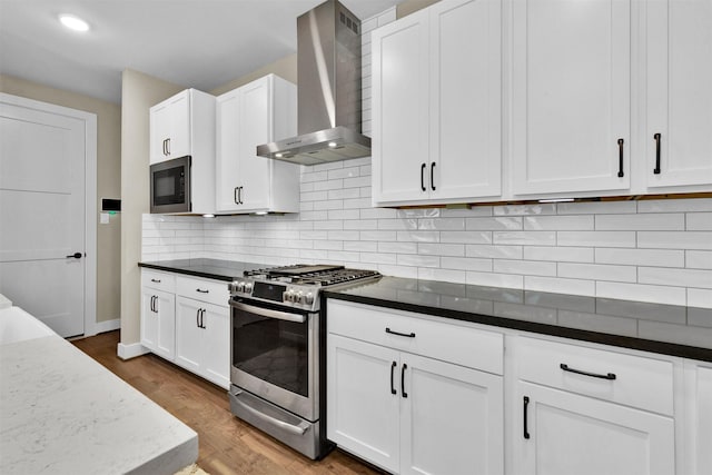 2609 Paul Quinn St, Houston, TX 77091 - kitchen with wall chimney range hood, gas stove, black microwave, wood finished floors, and white cabinets