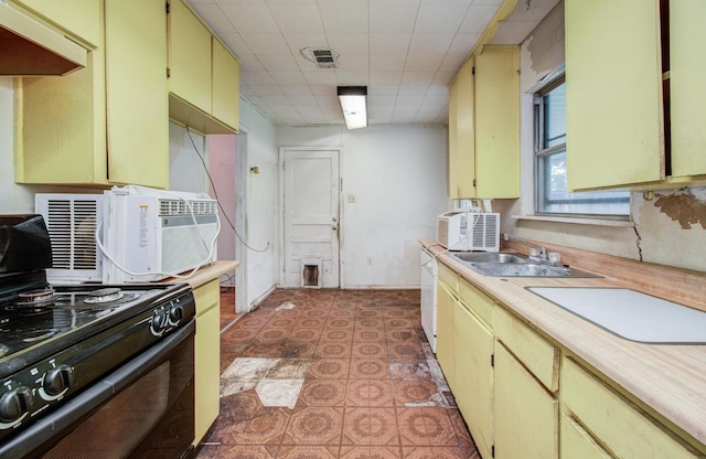kitchen with black electric range oven, light floors, light countertops, cream cabinets, and a sink