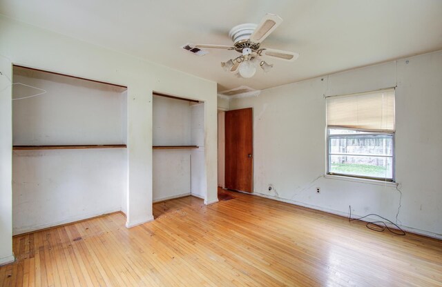 unfurnished bedroom with hardwood / wood-style flooring, two closets, baseboards, and ceiling fan