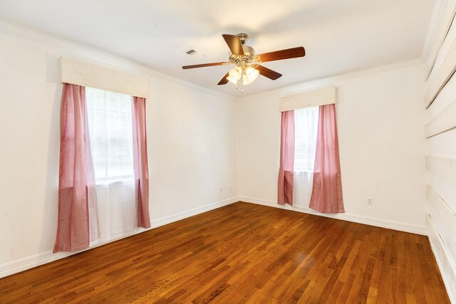 empty room with plenty of natural light, wood finished floors, ceiling fan, ornamental molding, and baseboards