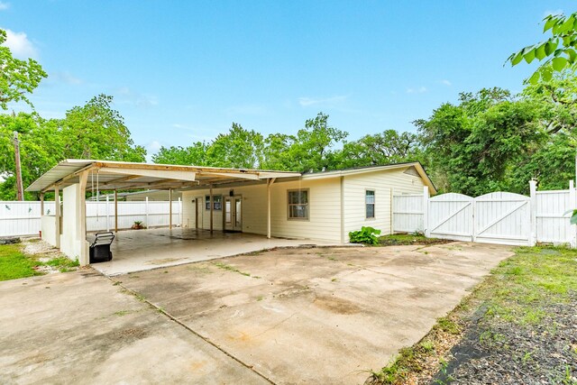 exterior space with a gate, fence, driveway, and a carport