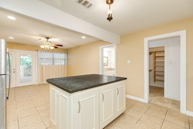 kitchen with light tile patterned flooring, dark countertops, white cabinets, ceiling fan, and a center island