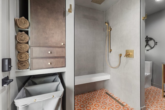 bathroom featuring a tile shower and toilet