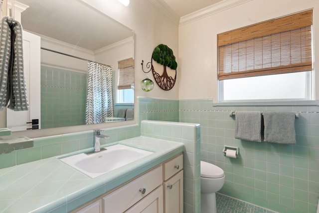 bathroom featuring toilet, crown molding, healthy amount of natural light, tile walls, and vanity