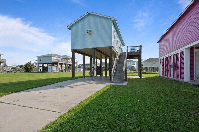 rear view of property with a carport, stairs, driveway, and a lawn