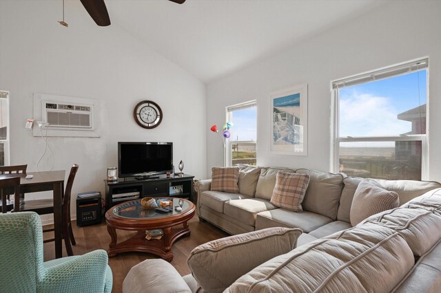living area with a ceiling fan, wood finished floors, plenty of natural light, an AC wall unit, and high vaulted ceiling