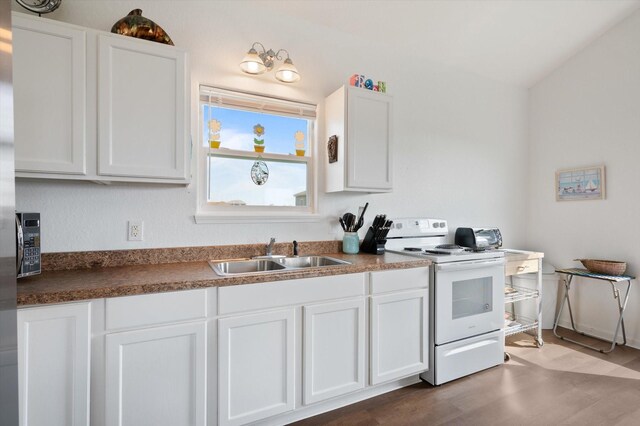 kitchen featuring white range with electric cooktop, a sink, white cabinets, wood finished floors, and dark countertops