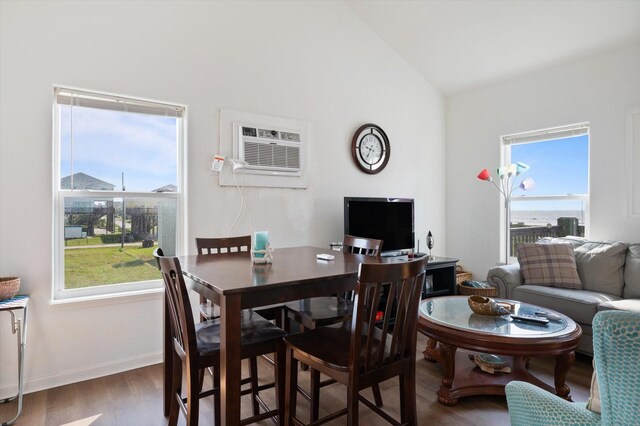 dining room featuring wood finished floors, vaulted ceiling, a wall mounted AC, and baseboards