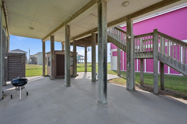 view of patio featuring stairway, a storage unit, and an outbuilding